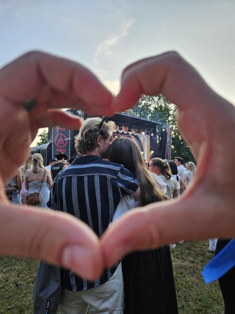 Jenny og Nikolai på en konsert, med hendene formet som et hjerte foran linsen
